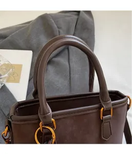 Detailed view of dark brown bucket bag showing suede texture and gold metal ring buckle