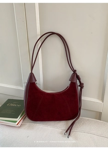 Detail of burgundy suede and leather patchwork hobo bag with knotted strap on fabric
