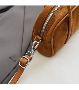 Detail view of brown suede bowling bag featuring silver zipper and adjustable strap