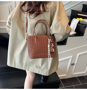 Detailed macro view of caramel brown pleated bucket bag with wheat grain embossed texture