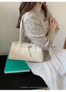 Detail der cremefarbenen rechteckigen Schultertasche mit Schnallenverzierung am Outfit