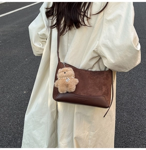 Detail of dark brown leopard-print shoulder bag featuring plush bear charm and sleek texture