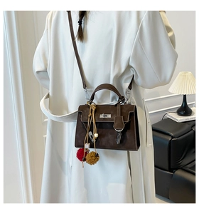 Detail of dark brown suede handbag featuring bohemian tassels and silver twist lock closure