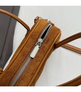 Detail of smooth silver zipper and brown suede texture on a stylish bowling bag