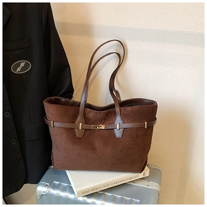 Detail view of brown suede tote bag with metal buckle on luggage and blazer