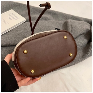 Close-up of bucket bag base with gold metal feet and faux shearling side details