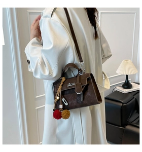Detail of vintage brown suede Kelly handbag with silver turn-lock and plaid charm