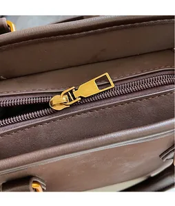 Detailed macro view of high-quality gold metal zipper on a dark brown leather bucket bag