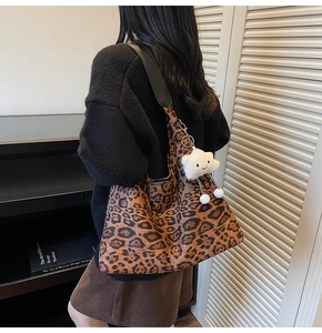 Detail view of large leopard print tote bag with a cute white cloud plush pendant