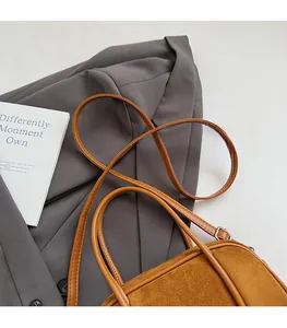 Detail view of a caramel suede baguette bag with an adjustable strap and fine texture