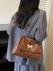 Sac bandoulière marron matelassé avec fermoir papillon en métal et chaîne sur mannequin