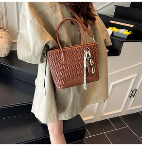 Detail of vintage brown woven bucket bag with elegant silk scarf and chain charm