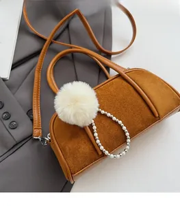 Detail of vintage caramel baguette bag with plush pom-pom and pearl charm on grey blazer