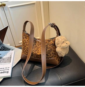 Detailed shot of leopard print shoulder bag with plush bear charm and brown leather trim