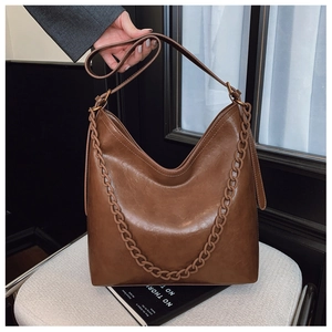 Detail view of large dark brown bucket bag with thick matching chain and matte PU leather
