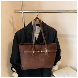 Detailed view of brown suede tote bag with leather straps and gold metal twist lock
