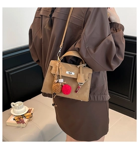 Detailed view of brown suede crossbody bag with decorative fur pompom charms