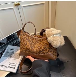 Detail of leopard print canvas bag with brown leather base and plush bear charm