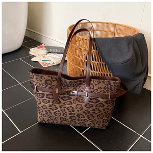 Detail of leopard print tote bag featuring silver metal buckle and deep brown leather straps