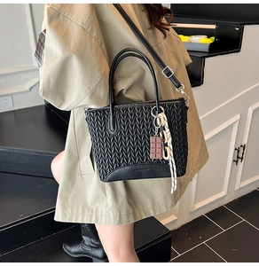 Detail of black pleated bucket bag with chic chocolate charm and woven chain decoration