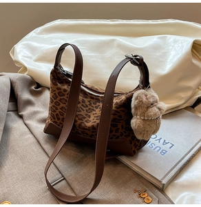 Detailed close-up of leopard print shoulder bag with brown leather trim and plush puppy charm