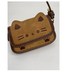 Detail of embroidered cat facial features on brown suede crossbody shoulder bag
