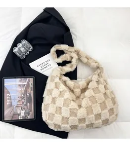 Detail of soft beige checkered faux fur tote bag on bed with modern accessories