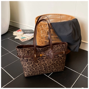 Detailed macro shot of leopard print tote bag featuring leather straps and gold buckle