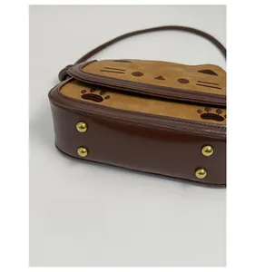 Detail showing vintage golden metal feet and cat paw embroidery on the bag bottom