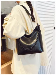 Upper body view of black hobo bucket bag with matte chain strap on model's shoulder