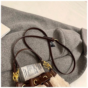 Detail view of cream plush bucket bag with leather trim and receipt-style tag