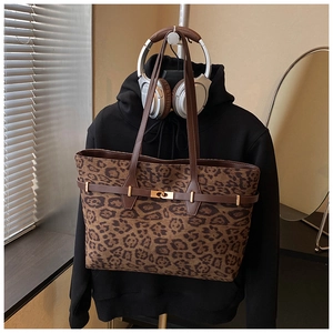 Detail of leopard print tote bag featuring a brown leather strap and golden metal twist lock