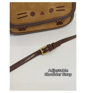Detail of adjustable brown leather shoulder strap with golden metal pin buckle on cat bag