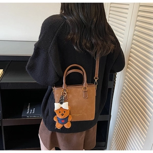 Detail view of brown faux leather tote with fashion gold lettering and bear charm