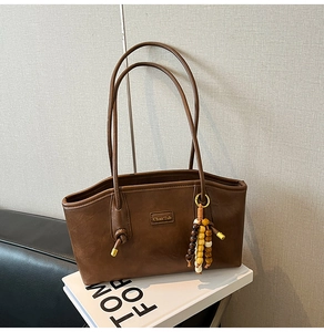 Detail view of vintage brown leather tote bag featuring brand logo and wood bead accessory