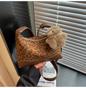 Detail of leopard print handbag featuring a plush bear pendant with a pearl necklace