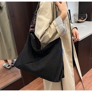 Detail of black corduroy tote bag with vintage geometric woven shoulder strap on model
