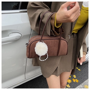 Close-up of brown suede bowling bag with fluffy white pompom and pearl chain charms