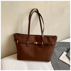 Detail view of the brown suede tote bag featuring a gold buckle closure and decorative belt