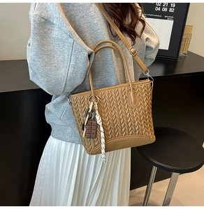Close-up of camel brown pleated bucket bag with V-shaped woven texture and long strap