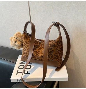 Detail of leopard print hobo bag with leather straps and a brown plush bear charm