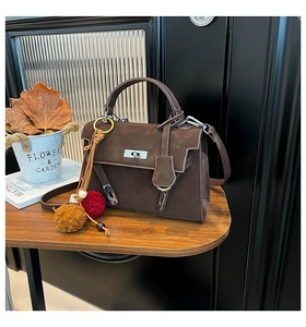 Detail shot of the vintage brown suede handbag with metal twist lock on a wooden table