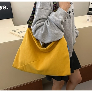 Detail of yellow corduroy tote bag featuring ethnic embroidery pattern strap and soft texture