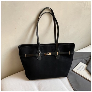 Detail of black faux suede tote bag with golden metal hardware and slim shoulder strap