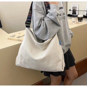 Detail of off-white corduroy tote bag featuring colorful ethnic style wide shoulder strap