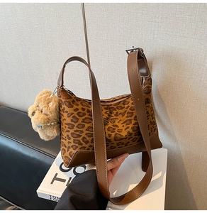 Detail of leopard print hobo bag with brown leather trim and cute plush bear charm