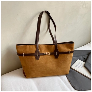 Detail of suede tote bag featuring a decorative dark brown strap and golden metal lock