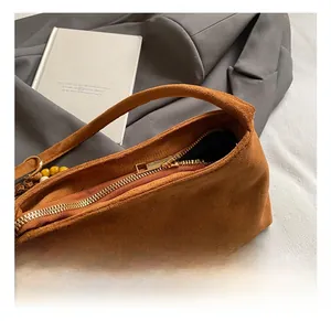 Close-up of golden metal zipper detail on brown faux suede shoulder bag with handle