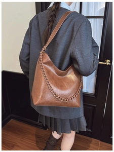 Detailed macro view of large retro brown bucket bag with thick chain and faux leather texture