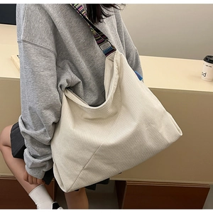 Detail of soft off-white corduroy tote bag with colorful ethnic style woven shoulder strap